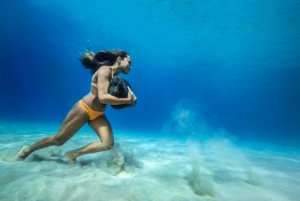 SURFER WANITA INI BERLATIH SURFING DENGAN BERJALAN DI BAWAH LAUT MENGGENDONG BATU 20KG